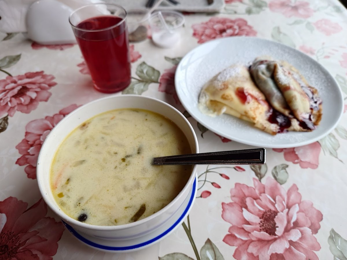 Kremowa zupa i talerz słodkich naleśników z dżemem oraz szklanka kompotu