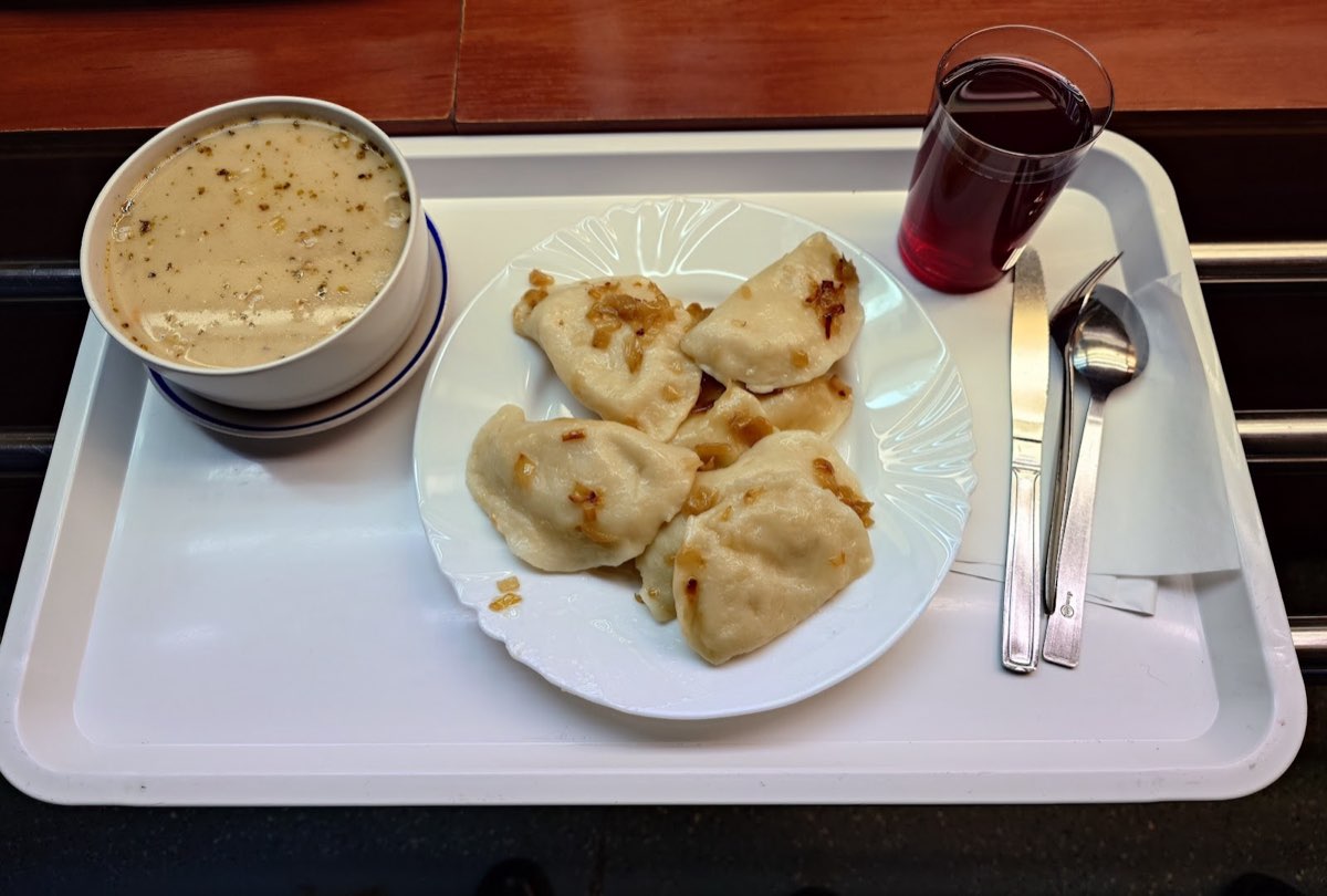Talerz pierogów z rumianą cebulką, miska zupy i szklanka kompotu